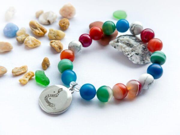 Bransoletka z agatu i howlitu z przywieszką  z przywieszką rysunkiem Beaty Pawlikowskiej Wąż Quetzalcoatl